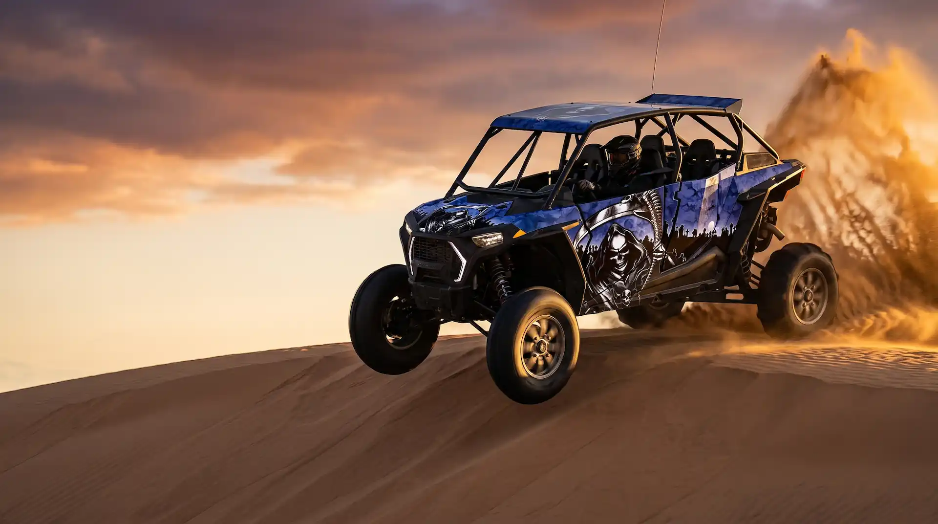 Four-seat UTV wrapped in the Reaper design launching off a sand dune